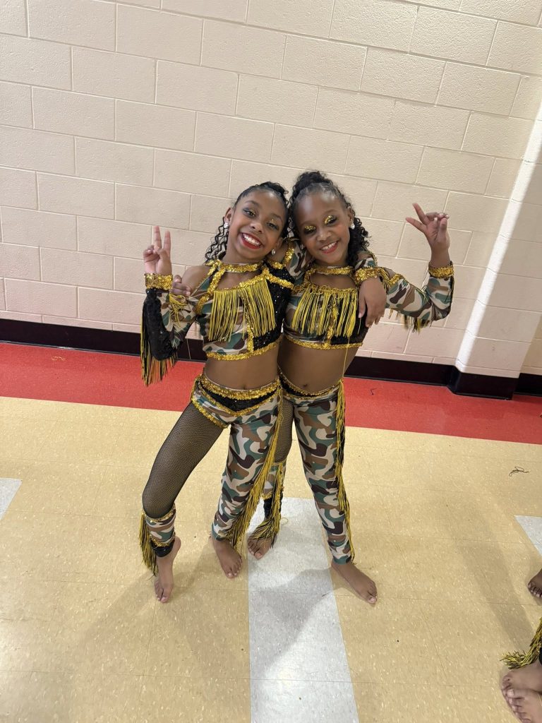 Two mini dancers pose for a photo behind the scenes of the Heavy Hittas majorette dance competition in Detroit, MI